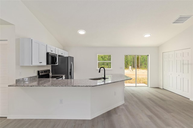 24375 NW Foxglove Ln, Dunnellon, FL 34431 - kitchen with appliances with stainless steel finishes, a sink, lofted ceiling, light wood-style floors, and light stone counters