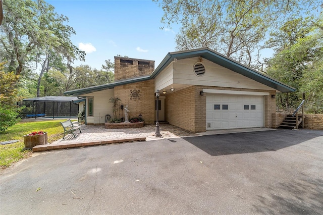 1179 SE 170th Ct, Silver Springs, FL 34488 - view of front of house featuring a chimney, asphalt driveway, brick siding, and a garage