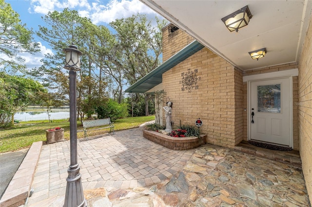 1179 SE 170th Ct, Silver Springs, FL 34488 - doorway to property with brick siding, a patio area, a water view, and a lawn
