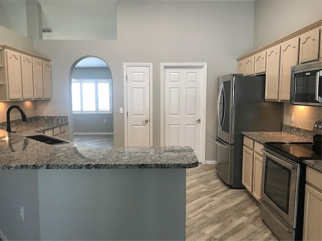11411 SW 138th Ln, Dunnellon, FL 34432 - kitchen with appliances with stainless steel finishes, a sink, baseboards, dark stone counters, and a high ceiling