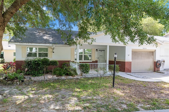 ranch-style house with a shingled roof, covered porch, an attached garage, and brick siding