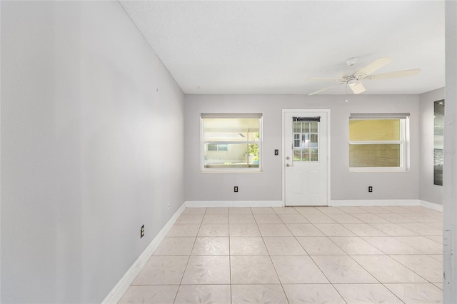 spare room featuring baseboards, ceiling fan, and light tile patterned flooring