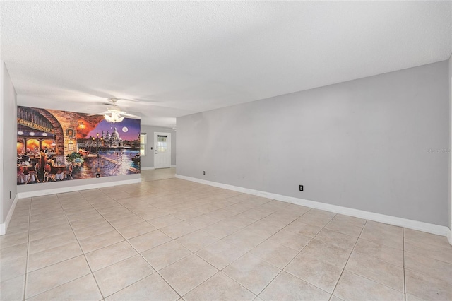 empty room featuring baseboards, ceiling fan, and light tile patterned flooring