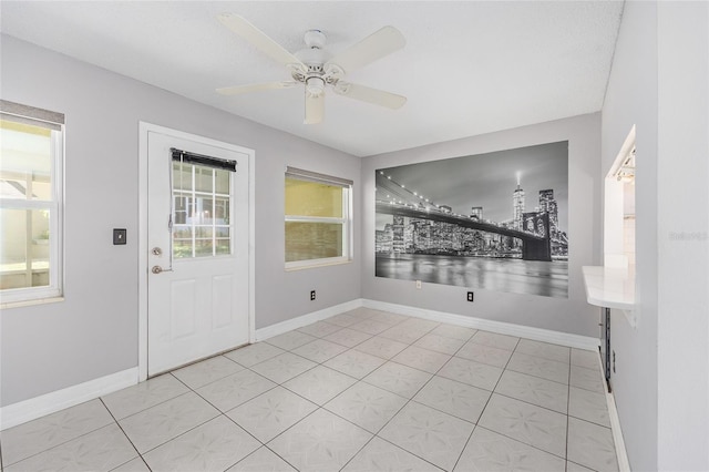 entrance foyer with baseboards, a ceiling fan, and light tile patterned floors