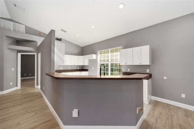 15087 SW 43rd Ct, Ocala, FL 34473 - kitchen with lofted ceiling, dark countertops, white cabinetry, light wood-style flooring, and baseboards