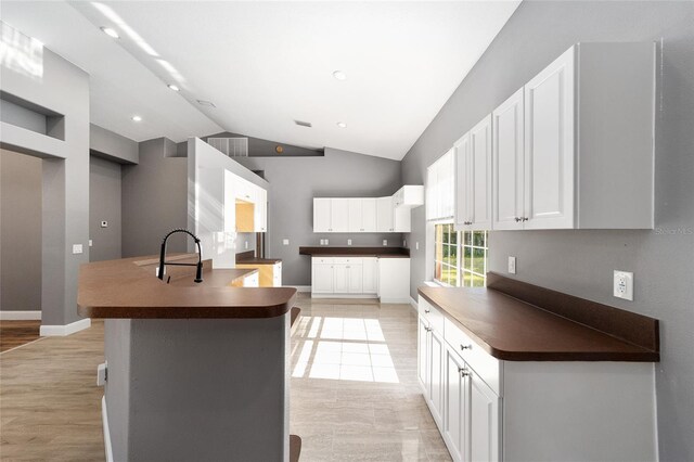 15087 SW 43rd Ct, Ocala, FL 34473 - kitchen with dark countertops, vaulted ceiling, white cabinets, a sink, and recessed lighting