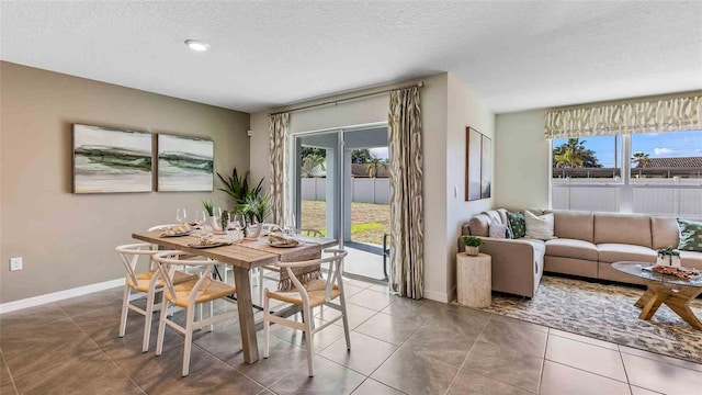 tiled dining area with baseboards, a wealth of natural light, and a textured ceiling