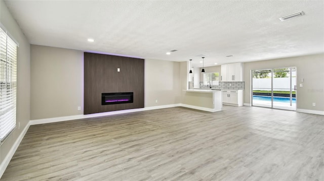 unfurnished living room with visible vents, recessed lighting, light wood-style floors, and baseboards
