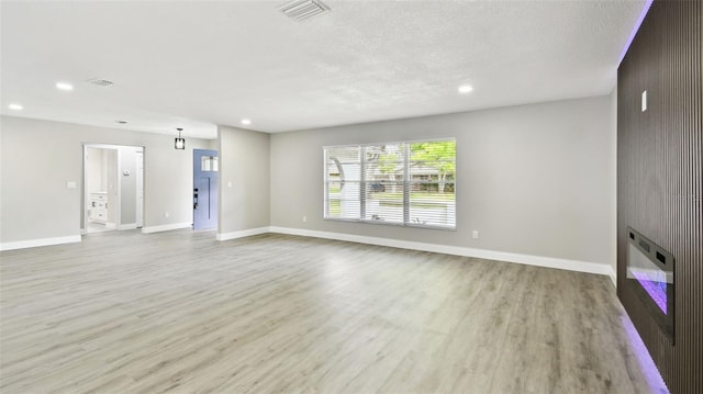 unfurnished living room with visible vents, recessed lighting, baseboards, and wood finished floors