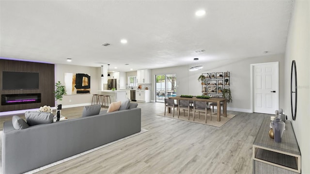 living area featuring recessed lighting, baseboards, and light wood finished floors