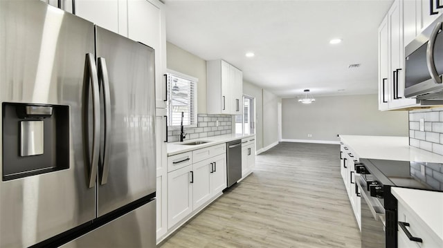 kitchen with decorative backsplash, baseboards, light countertops, a sink, and appliances with stainless steel finishes