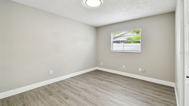 empty room featuring baseboards, a textured ceiling, and wood finished floors