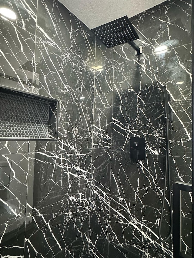 details featuring a textured ceiling and a marble finish shower