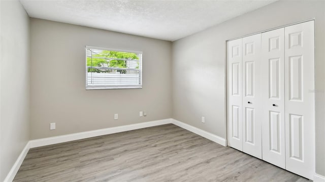unfurnished bedroom featuring a closet, baseboards, and wood finished floors