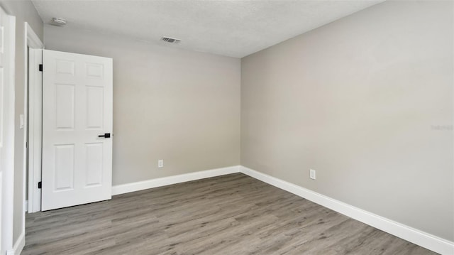 empty room featuring baseboards, visible vents, and wood finished floors