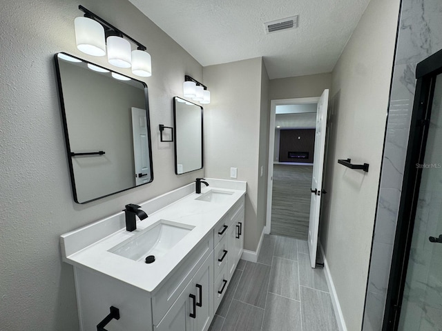 full bath with baseboards, a sink, a textured ceiling, and visible vents