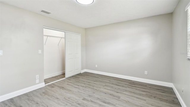 unfurnished bedroom featuring visible vents, baseboards, wood finished floors, and a closet