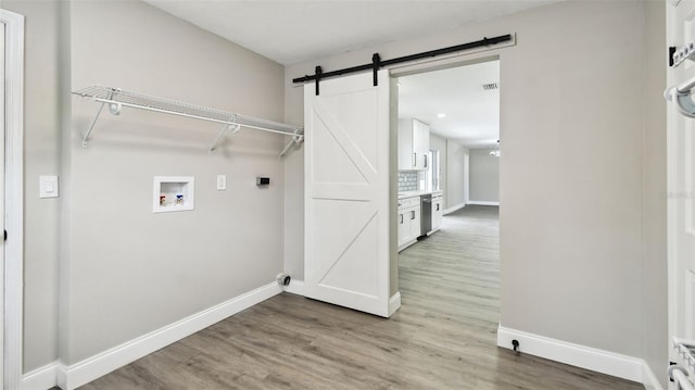 clothes washing area with baseboards, laundry area, hookup for a washing machine, and a barn door
