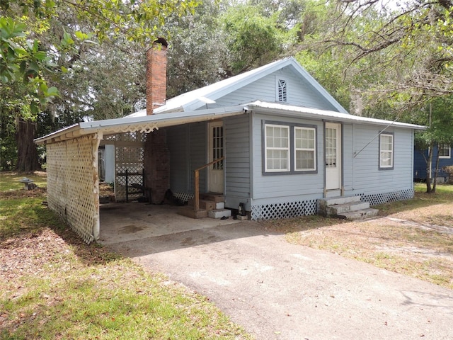 219 SE 3rd Ave, Williston, FL 32696 - bungalow-style house featuring a chimney, entry steps, driveway, and an attached carport