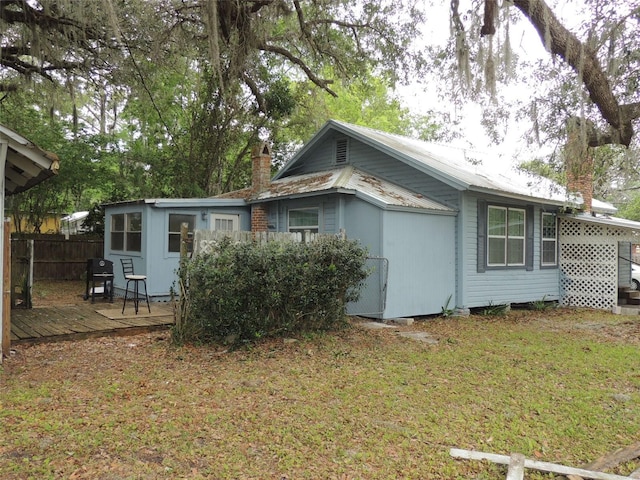 219 SE 3rd Ave, Williston, FL 32696 - view of property exterior featuring a chimney, fence, a wooden deck, and metal roof
