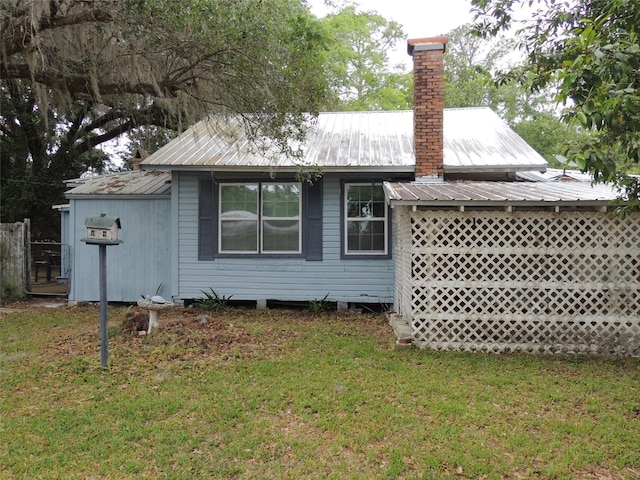 219 SE 3rd Ave, Williston, FL 32696 - rear view of house featuring a lawn, fence, a chimney, and metal roof