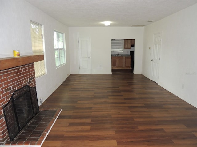 219 SE 3rd Ave, Williston, FL 32696 - unfurnished living room featuring dark wood finished floors and a fireplace