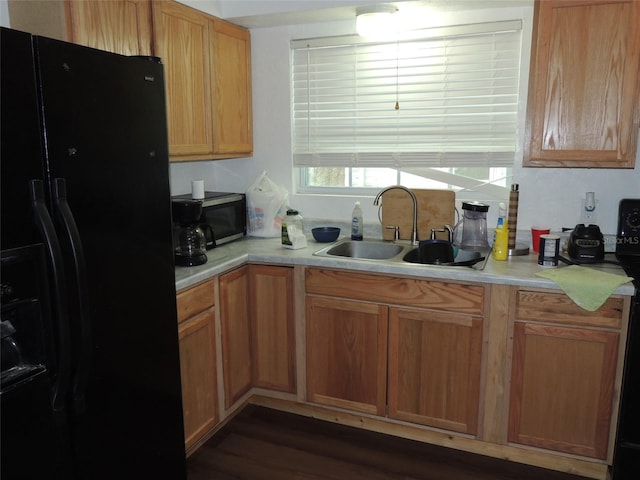 219 SE 3rd Ave, Williston, FL 32696 - kitchen featuring stainless steel microwave, a sink, dark wood-style flooring, black fridge, and light countertops