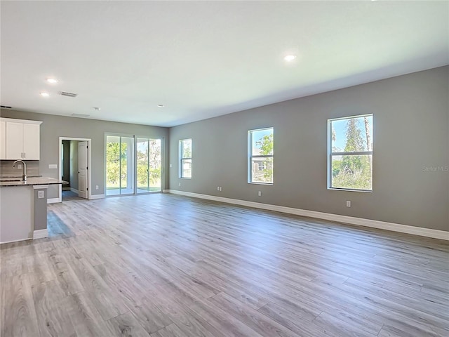 2423 Sadnet Ln, North Port, FL 34286 - unfurnished living room featuring light wood-type flooring, recessed lighting, a sink, and baseboards