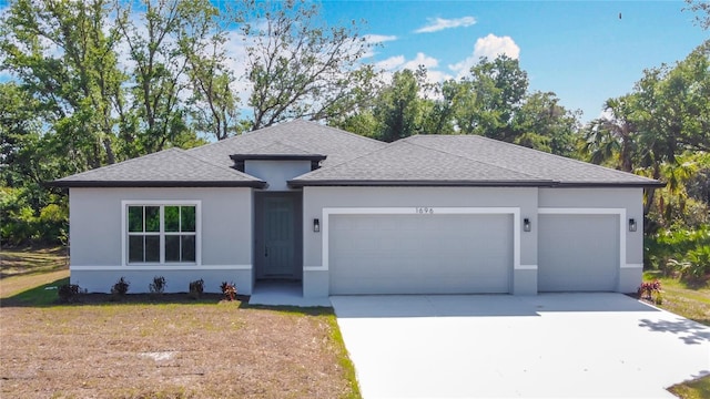 prairie-style home with concrete driveway, a shingled roof, a front yard, an attached garage, and stucco siding