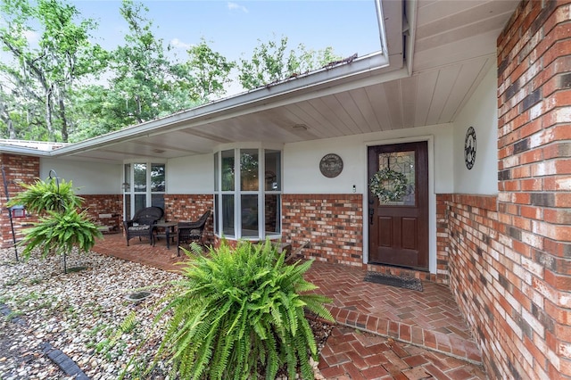 property entrance featuring a porch and brick siding