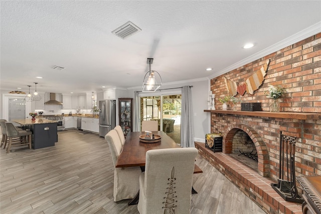 dining room featuring visible vents, a brick fireplace, ornamental molding, recessed lighting, and light wood-style flooring
