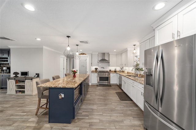 kitchen with wall chimney range hood, stainless steel appliances, visible vents, and a sink