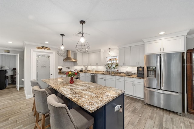 kitchen featuring wall chimney range hood, decorative backsplash, appliances with stainless steel finishes, and ornamental molding