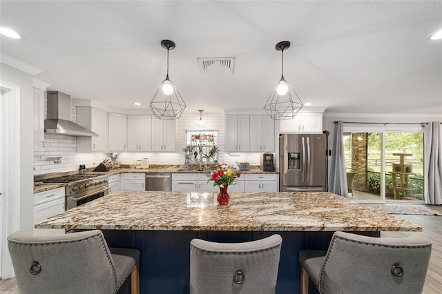 kitchen with backsplash, visible vents, wall chimney exhaust hood, stainless steel appliances, and white cabinetry