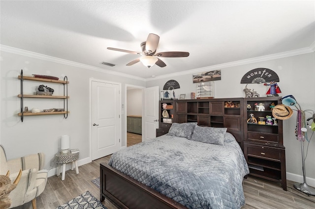 bedroom with baseboards, ornamental molding, light wood-style flooring, and visible vents