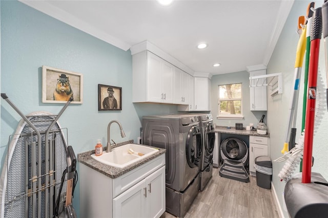laundry area with cabinet space, a sink, light wood-style floors, ornamental molding, and washer and dryer