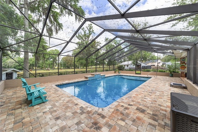 pool featuring an outdoor structure, glass enclosure, a patio area, and a shed