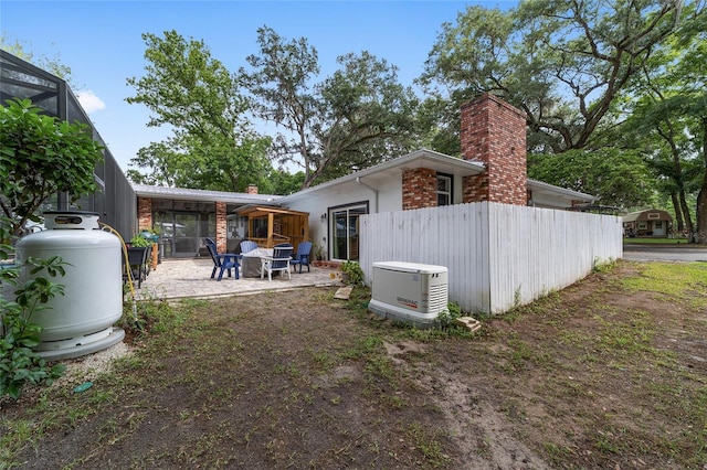back of house with a patio area, fence, and a chimney