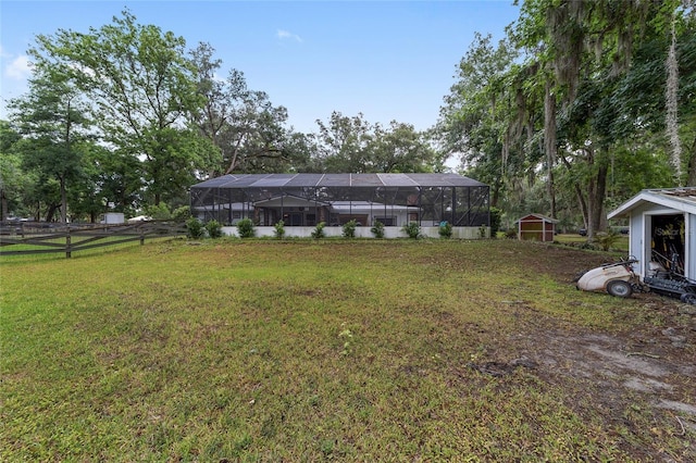 view of yard featuring a storage shed, fence, glass enclosure, and an outdoor structure