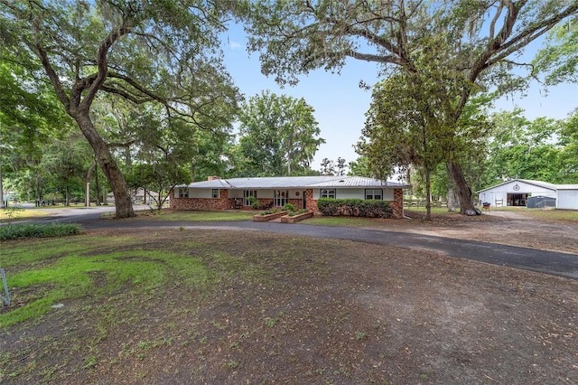 single story home with brick siding, a chimney, and aphalt driveway