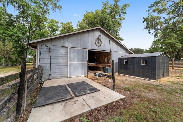 view of outdoor structure with central AC, fence, and an outdoor structure