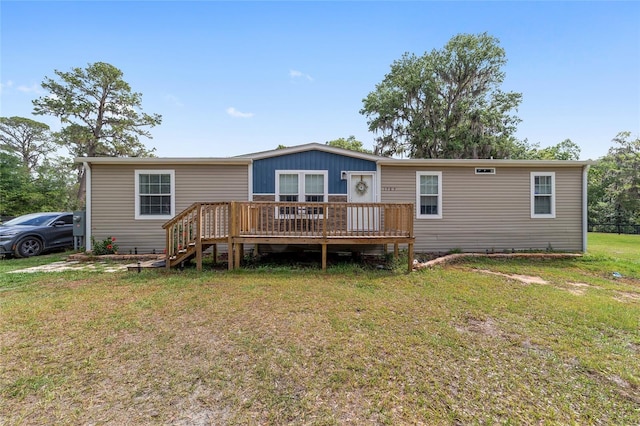 back of property with a lawn and a wooden deck