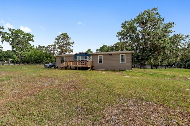 back of property featuring fence, a wooden deck, and a yard