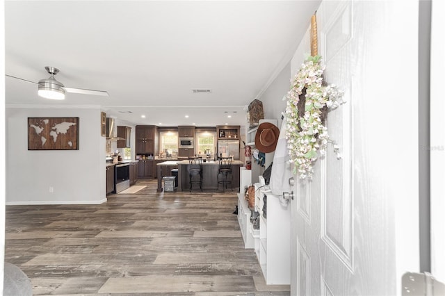 entryway with visible vents, crown molding, wood finished floors, and ceiling fan