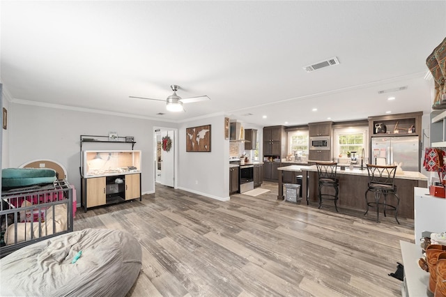 living room with ceiling fan, recessed lighting, light wood-type flooring, visible vents, and ornamental molding