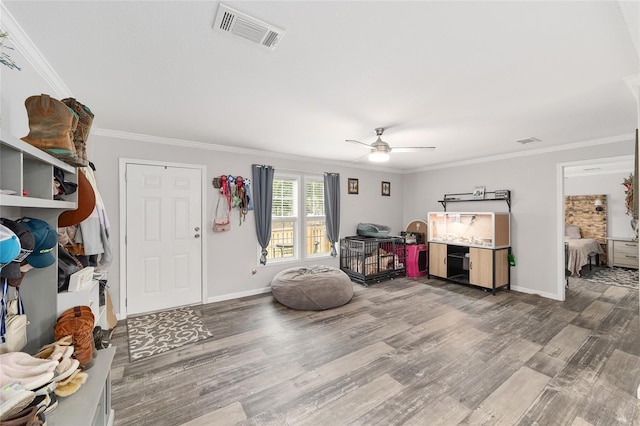 interior space featuring visible vents, a ceiling fan, crown molding, and wood finished floors