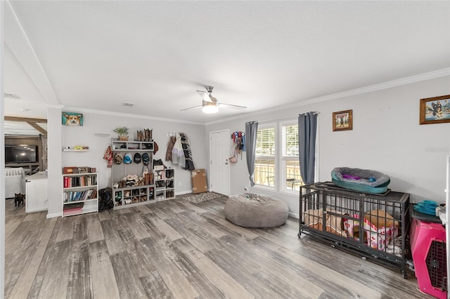 living area with crown molding, ceiling fan, baseboards, wood finished floors, and visible vents