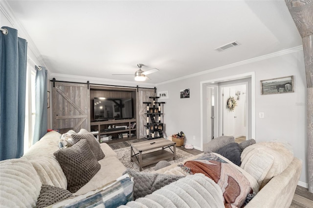 living area with baseboards, ornamental molding, a barn door, and visible vents
