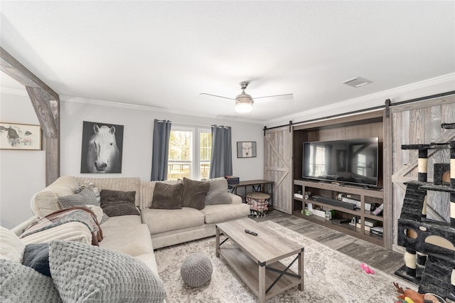 living area featuring crown molding, wood finished floors, a barn door, and visible vents