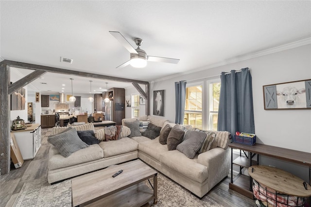 living area featuring visible vents, ornamental molding, a ceiling fan, and wood finished floors